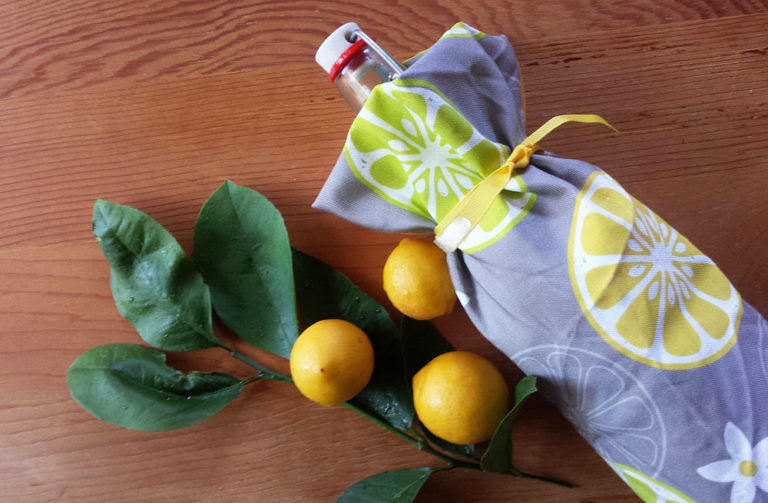 Bottle gift wrapped with Orange, Orange, Lemon, Lime tea towel by Lellobird